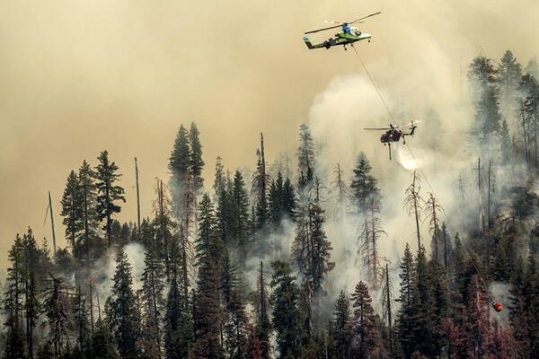 Seen from unincorporated Mariposa County, Calif., a helicopter drops water...
