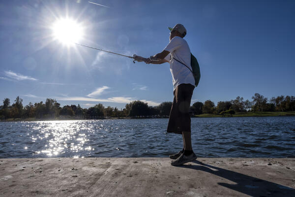 George Hernandez, of Long Beach, fishes at Lake Balboa Park...