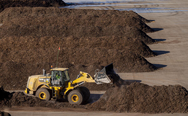 A tractor turns green waste at a composting facility recently...