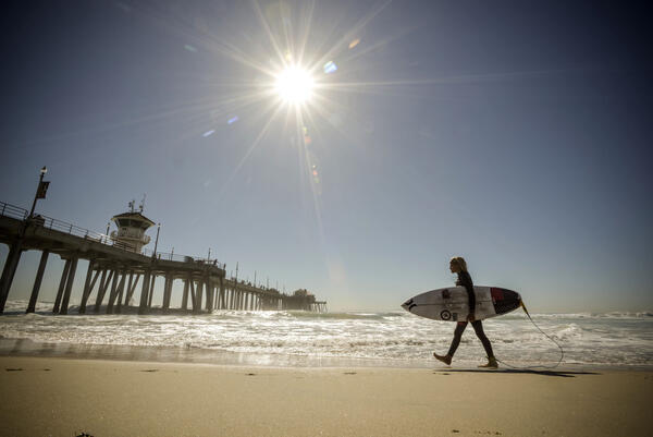 A surfer walks along the shore during unseasonably hot weather...
