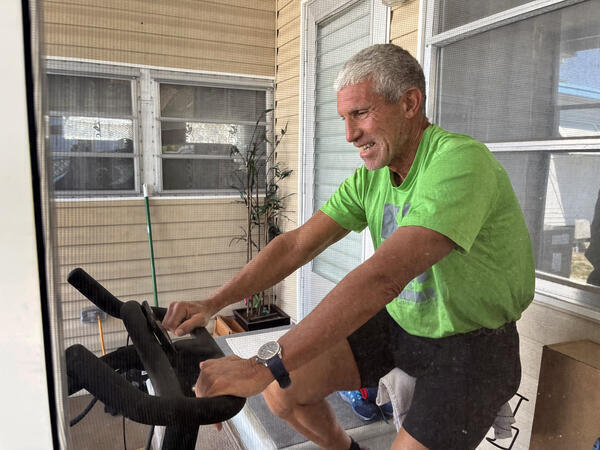 Rick Singer works out on a Peloton bike while being...