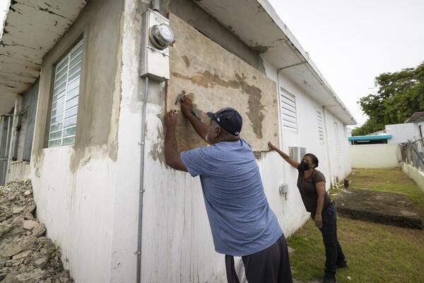 Residents attach protective plywood to a window of their home...