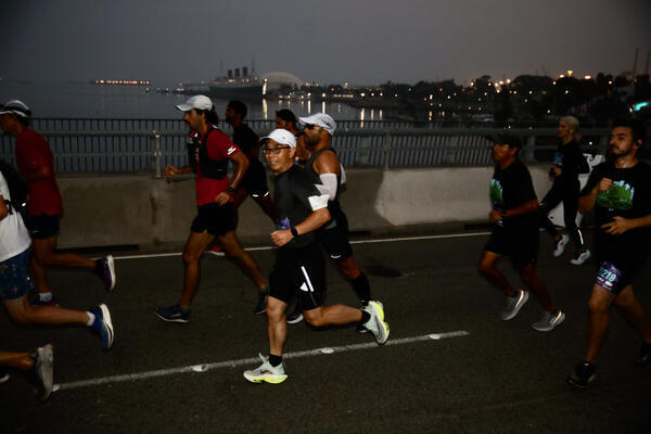 Runners cross the Queensway Bridge before sunrise on Sunday, Oct....