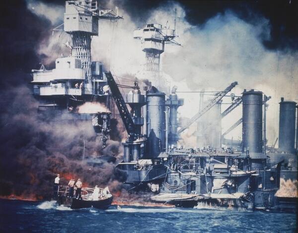 A small boat rescues a USS West Virginia crew member from the water after the Japanese bombing of Pearl Harbor, Hawaii on Dec. 7, 1941 during World War II. Two men can be seen on the superstructure, upper center. The mast of the USS Tennessee is beyond the burning West Virginia. (AP Photo)