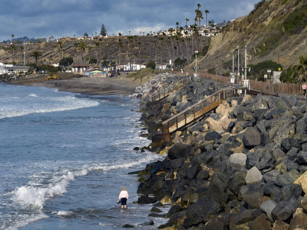 A beachgoer makes her way across north San Clemente, CA,...